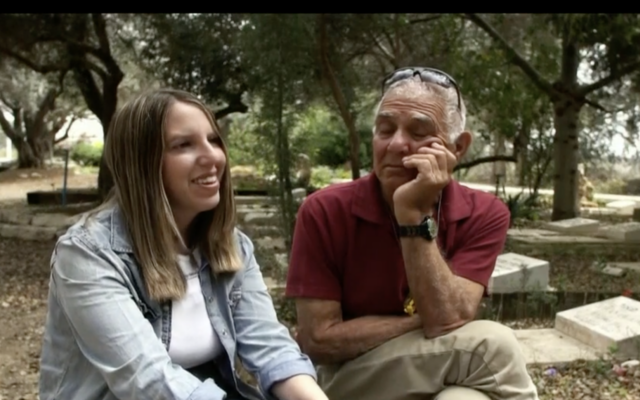 Freed hostages Doron Katz-Asher, left, sits near the grave of her mother Efrat Katz, alongside Efrat's partner, former hostage Gadi Mozes, in Kibbutz Revadim, during an interview broadcast by Channel 12 on May 23, 2025. (Screen capture: Channel 12)